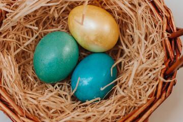 Colored easter eggs in a brown basket of twigs