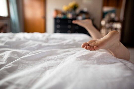 Toddler having fun sliding off freshly made bed
