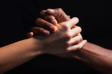 Male and female hands with different skin tones holding each other