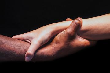 Male and female hands with different skin tones holding each other