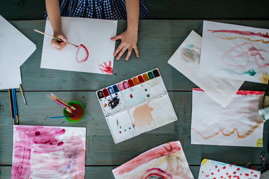over head view of young girl painting bright pictures on table