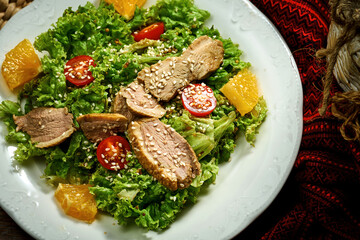 Salad with duck breast, tomatoes and sauce in a white plate.