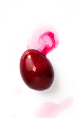 Dye purple color easter egg, isolated on white. Purple easter egg and liquid food coloring on white background. Close up shot.