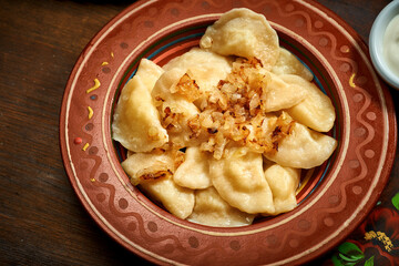 Traditional Ukrainian varenyky stuffed and fried onions in clay dishes. Ukrainian cuisine. Close up