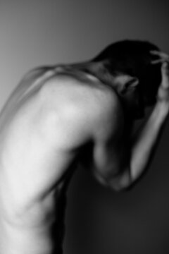 Young man holds his head with both hands. Soft focus