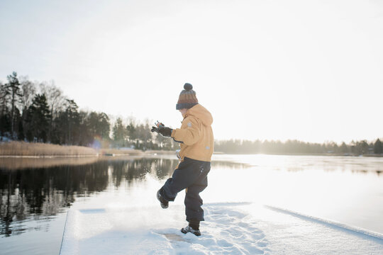 young boy playing in the snow at sunset by the Baltic sea in Sweden