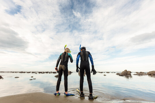 Rear view of children with snorkels standing on beach in New Zealand