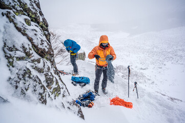 Men preparing gear for winter ski-mountaineering in puffy jacket