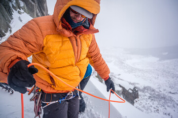 Men preparing gear for winter ski-mountaineering in puffy jacket
