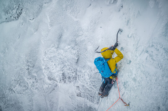 Male mountaineer climbing technical ice wall in cold temperatures