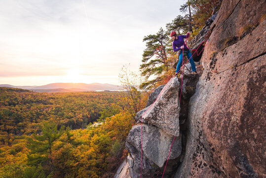Man getting ready to rappel with mountains and foliage in background