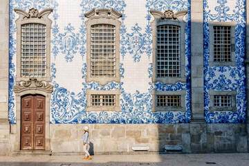 Tourist walking, azulejos tiles over Chapel Of Souls, Porto, Portugal - 571497451