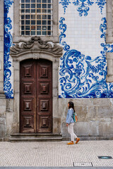 Tourist walking, azulejos tiles over Chapel Of Souls, Porto, Portugal