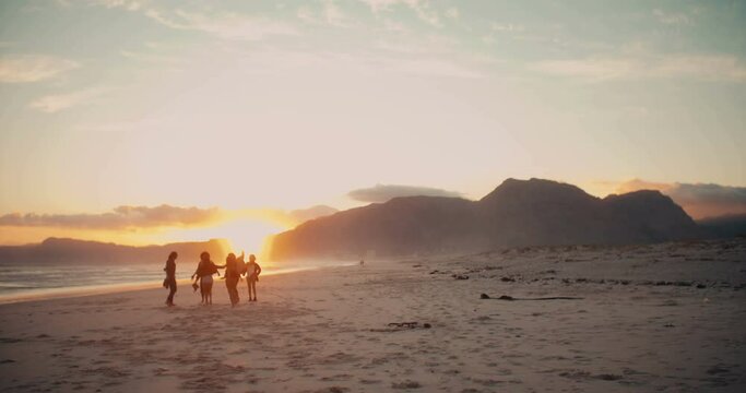Teenager friends with shadow cast dancing at sunset on the beach