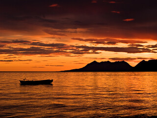 Mountains and rowboat in orange sunset in Northern Norway