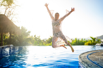Blonde woman jumping happily on a pool