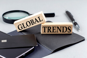 GLOBAL TRENDS text on wooden block on black notebook , business concept