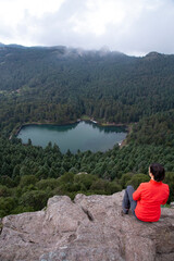 Female mexican hiker sitted on edge of cliff, admiring the view