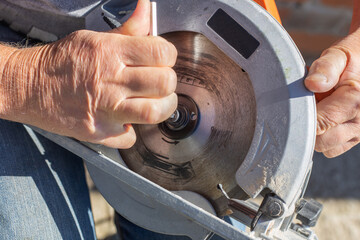 a man screws a saw blade with a hexagon on a circular miter saw