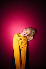 A happy young blond woman is laughing while standing in front of the magenta background. Viva magenta.