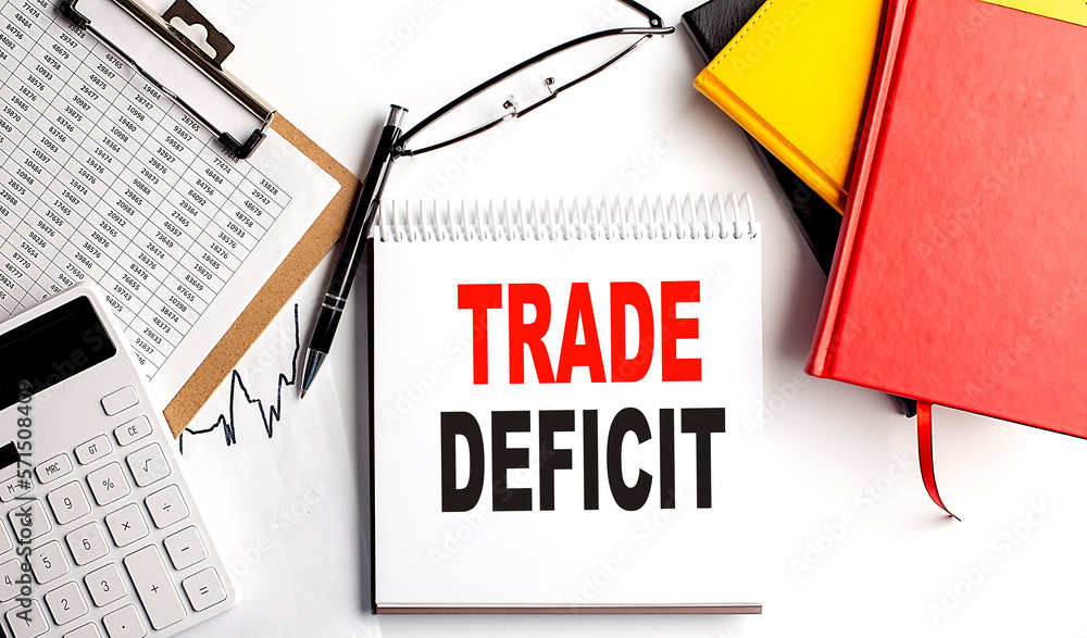 Aufkleber trade deficit text on notebook with clipboard and calculator on white background
