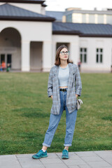 young female student in a jacket and jeans on campus