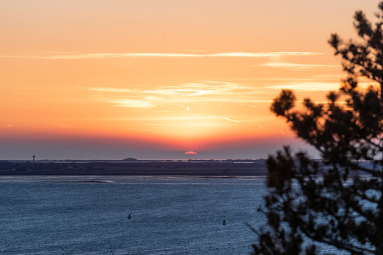 Red rim of the sun gleaming out from the haze during sunset