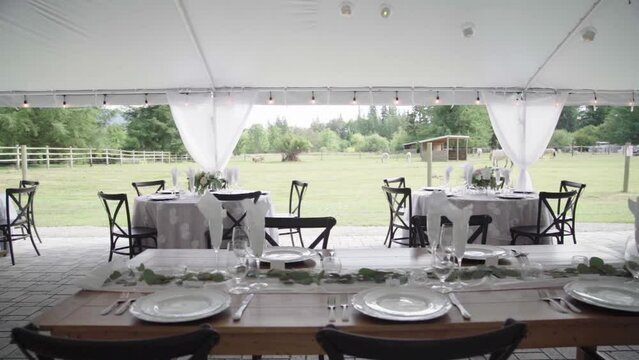 Elegant banquet tables for a luxurious outdoor wedding. Big tent, lot of opulence. Panning. 