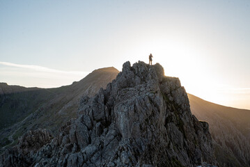 Un homme au sommet d'une montagne au soleil couchant