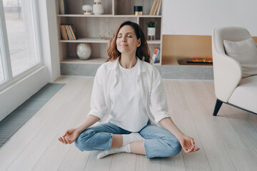 Girl is sitting in lotus pose with her eyes closed. Stress relief, wellbeing and peace concept.