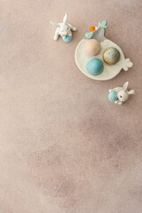 Fototapeta na wymiar Colorful Easter eggs and cute bunnies on a pastel pink background, top view, copy space
