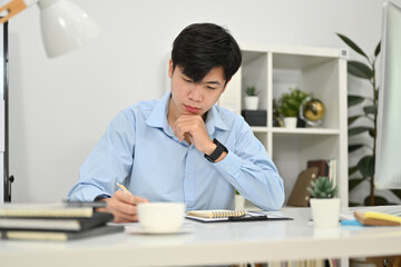 Focused millennial businessman managing company investment strategy and using laptop in modern office