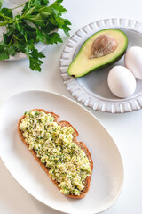 Toast from two boiled eggs and avocado with herbs. The concept of proper and healthy nutrition. Useful breakfast.