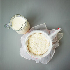 Fresh ricotta cheese in a white sieve and milk in a glass jug, Soft ricotta cheese, cooking process , process of making home-made cheese in the workshop, Cheese for package design 