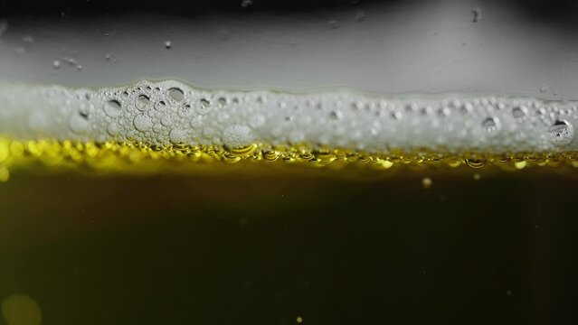 head of a light beer with foam and bubbles floating to the top