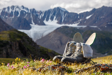 Trekking boots with insoles and socks dry on the background of a mountain valley. Boots in focus,...