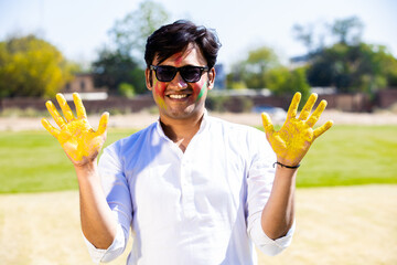 Happy indian man showing his painted hands celebrating holi festival of india.