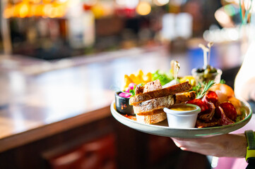 Waiter holda plate with tasty appetizers in restaurant