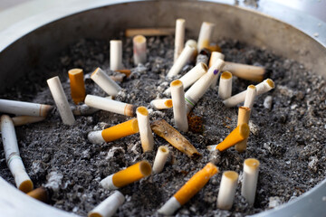 Cigarettes and ash on dirty sand in trash tray