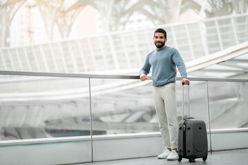 Fototapeta premium Happy Tourist Man Posing With Travel Suitcase At Modern Airport