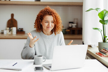 Marketing specialist sitting at kitchen table with copybook, coffee cup and phone, looking at...