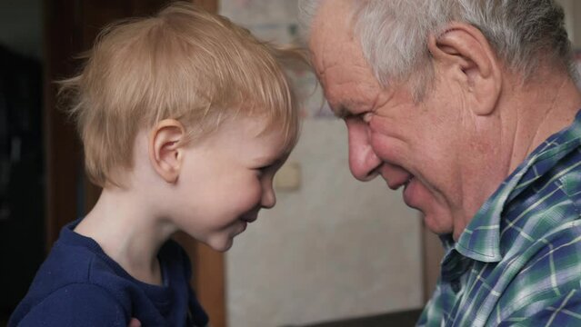 Old man grandfather with little grandson baby. They smile play make grimaces. Children fun positive emotions from leisure. Generations in family. Happy to be together. Visit relatives, joy of meeting