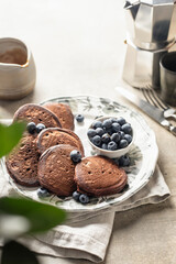 Healthy breakfast. Pancakes with fresh blueberries and mint leaves served with coffee in morning light, greenery in blur . Copy space