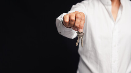 Fototapeta premium Hand of a businessman or real estate agent with keys from a new house hanging on the finger