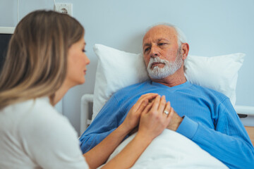 Obraz premium In the Hospital Ward Recovering Father is Visited by Daughter. Senior Sick Man Sleeping in Bed Daughter Sits Beside, Worrying. Modern Private Ward. Family Values. 