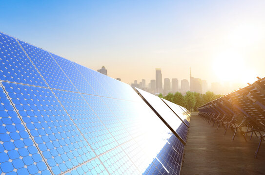 Solar panel farm on green field with cityscape background
