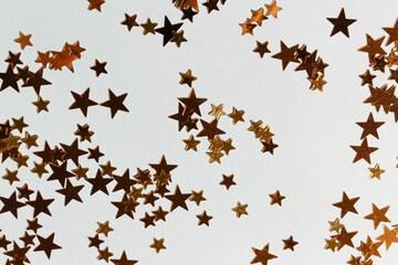 Golden stars confetti scattered on a blue pastel background.