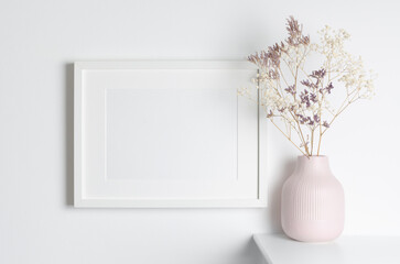 White frame mockup with dry flowers in vase, blank mockup for artwork presentation