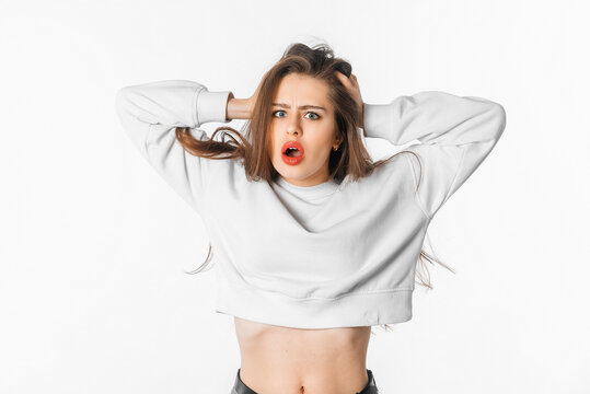Image of shocked anxious woman in panic, grabbing her head and worrying, standing frustrated and scared against white background. Stress concept