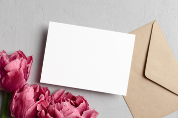 Fototapeta premium Blank wedding invitation card mockup with envelope and pink tulip flowers